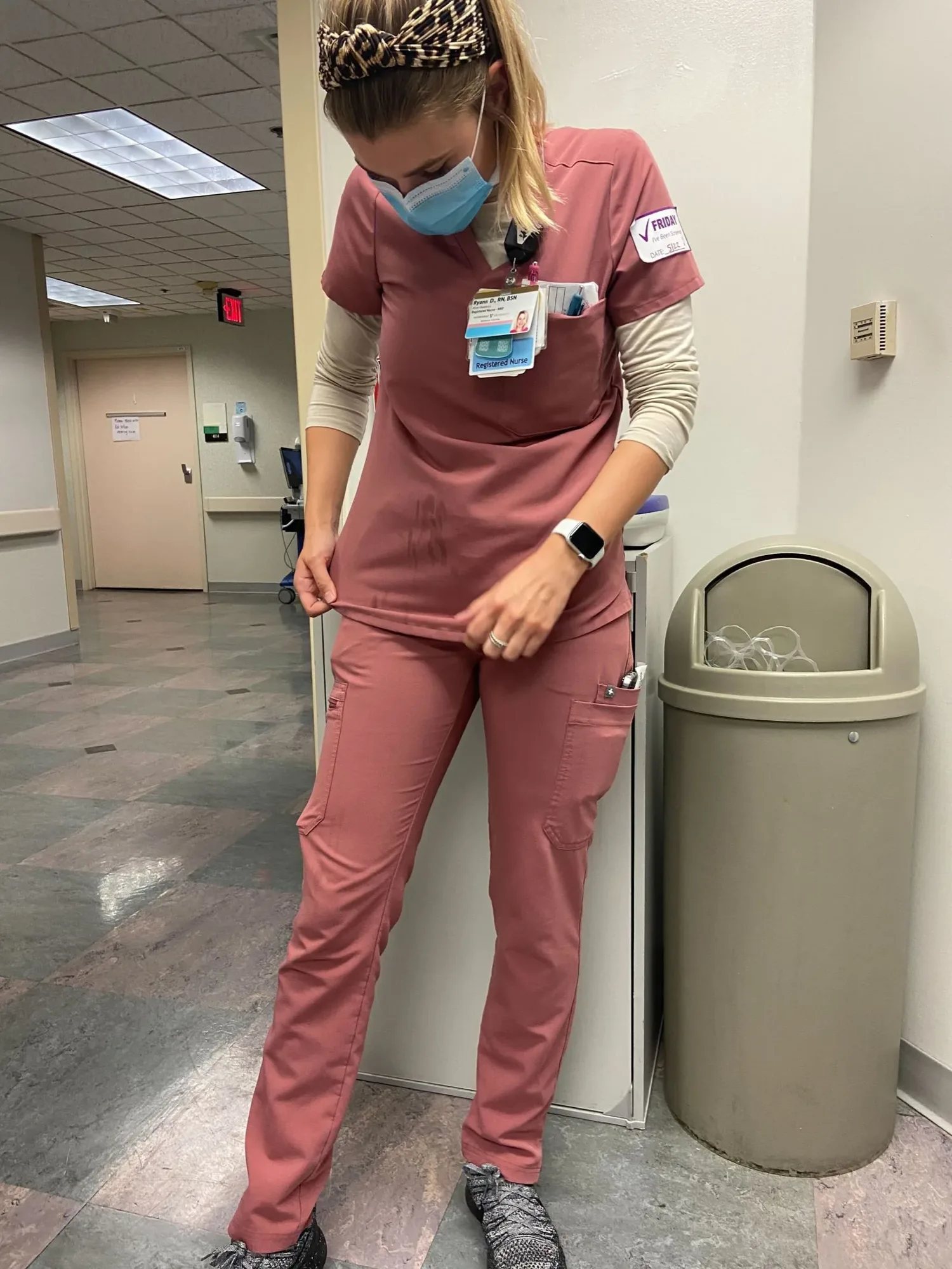 A nurse wears pink FIGS scrubs in a healthcare facility.