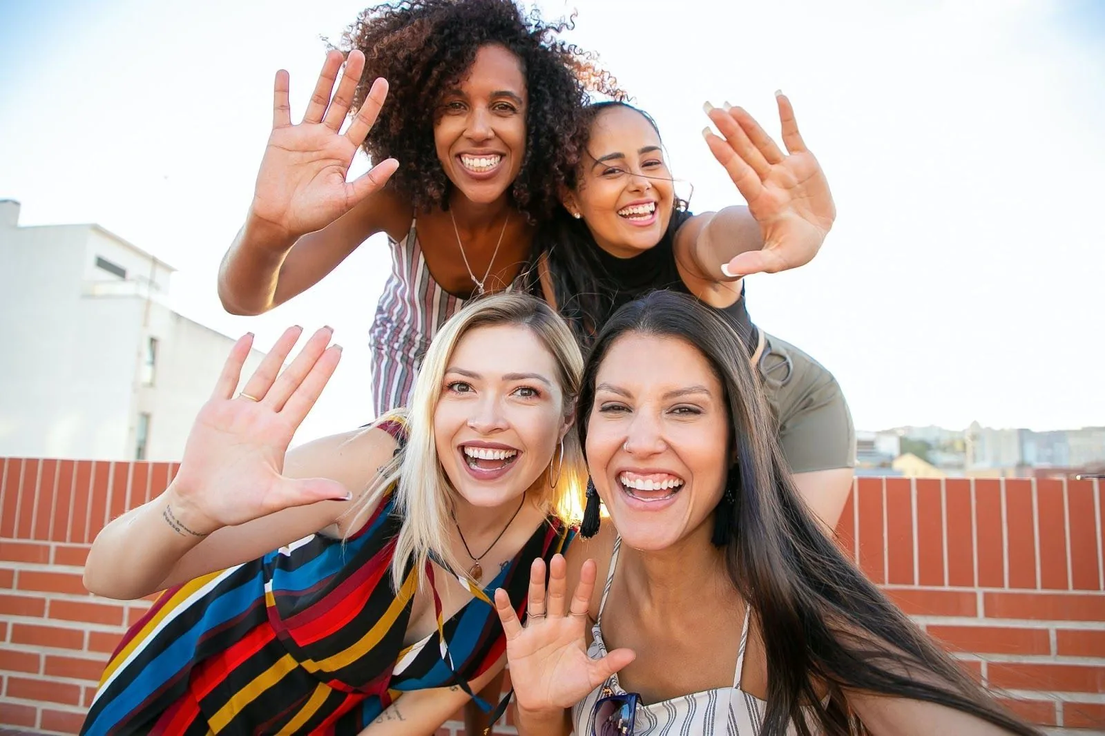 Four cheerful healthcare professionals waving at the camera, symbolizing the joy and camaraderie found in making new friends while on a travel assignment.