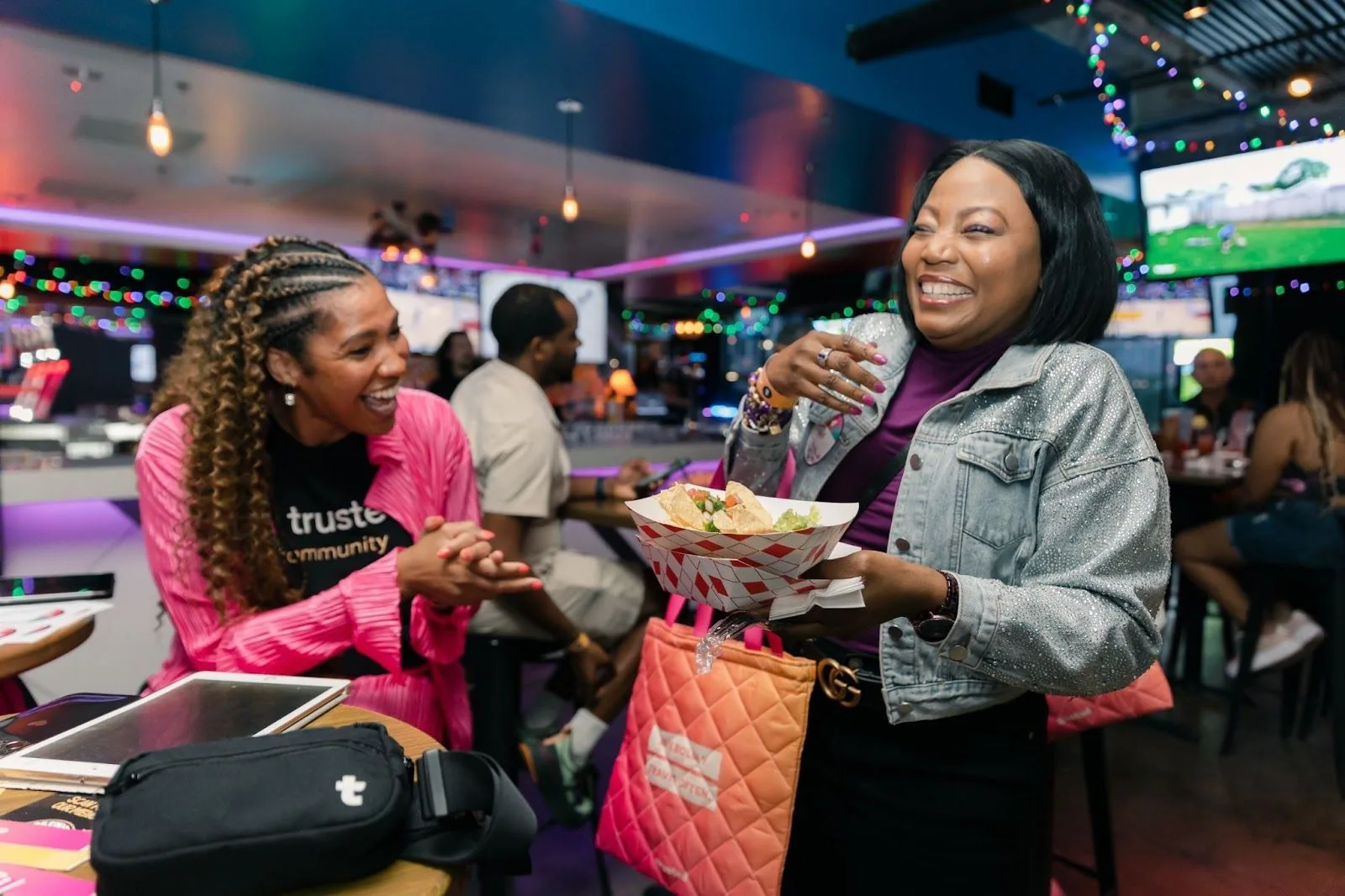 Two healthcare professionals from the Trusted Community sharing a joyful moment with nachos and drinks, embodying the camaraderie and support found within the network.