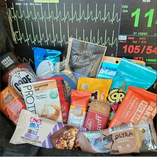 A selection of various snacks and protein bars arrayed on a background that resembles an ECG monitor display, part of the ROSCBox subscription for healthcare workers